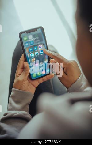 A young adult man in a grey shirt standing with a smart phone in his hand Stock Photo