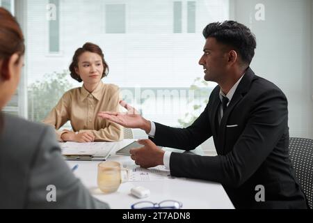 Young entrepreneur sharing ideas with colleagues in meeting Stock Photo