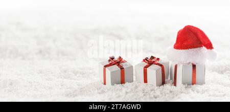 Christmas gift boxes and Santa Claus hat in snow Stock Photo