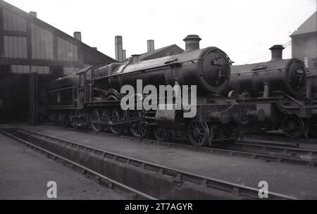 1950s, historical, two steam locomotives of the era outside a railway shed, England, UK. Number 5959 was a 4-6-0 GWR locomotive 'Mawley Hall' which entered service in 1936. It was withdrawn in 1962. Beside it, a GWR locomotive 9306, a Churchward 2-6-0 which entered service in 1932. Stock Photo