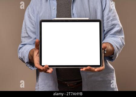 A businessman holding a tablet with a blank screen, ready for mockup presentations, isolated on a neutral background. Stock Photo