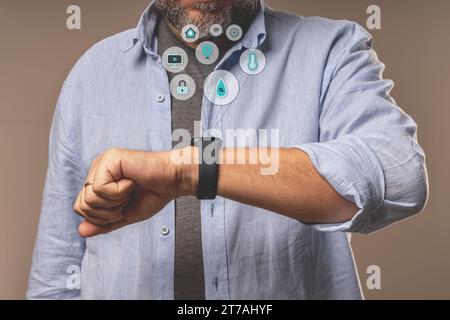 Close-up of a man using a smartwatch with graphic icons representing smart home apps, emphasizing the wearable technology concept. Stock Photo
