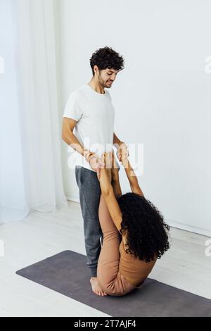 a man stretches a woman's arms in yoga training acrobatics Stock Photo