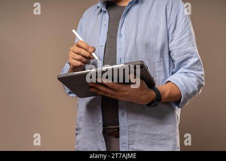 A casual businessman engaging with a digital tablet using a stylus, showcasing a modern approach to business tasks and digital artistry. Stock Photo