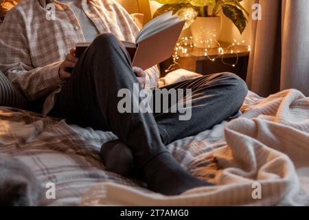 A caucasian man relaxing at home, reading a book in bed Stock Photo