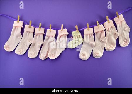 World Prematurity day concept. Normal size and tiny socks on rope on purple background Stock Photo