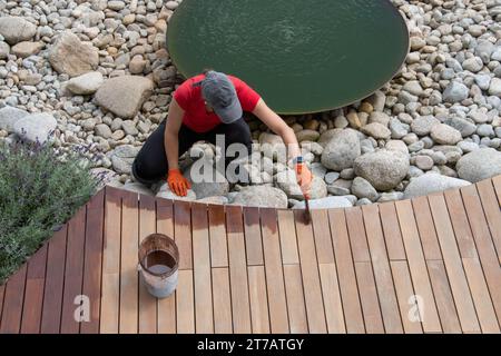 Wood oil application, workwoman maintaining exterior house garden terrace, spring work around the house Stock Photo