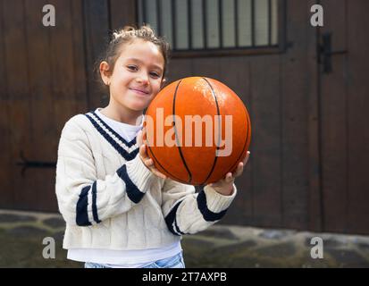 Close-up of happy smiling girl with basketball in the street Stock Photo