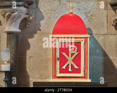 Red tabernacle (with the chi-rho monogram for Jesus Christ) on a wall of the east end chapel in the medieval christian cathedral at Lincoln, England. Stock Photo