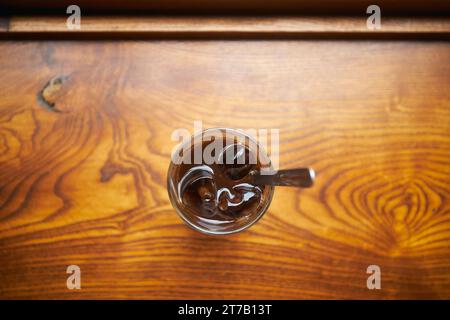 Close-up of glass of Vietnamese iced coffee on wooden table. Selective focus on ice cubes. Still life with coffee in Hanoi in Vietnam. Stock Photo