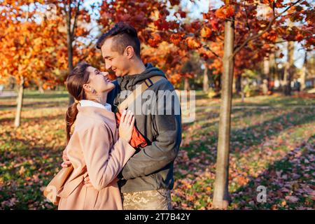 Young man soldier in military uniform and his wife walking in autumn park. Couple hugging after long separation outdoors. Homecoming Stock Photo