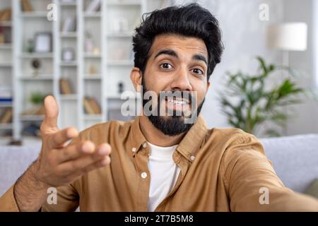 Hindu male student talking on video call on the phone, talking with family, discussing work issues, answering distance learning, camera view. Stock Photo