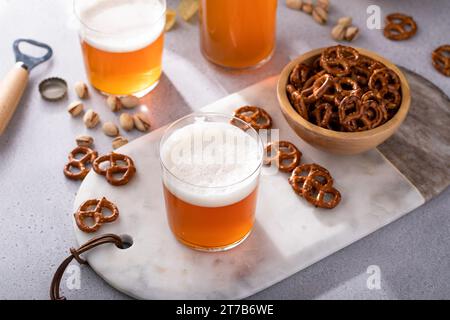 Lager beer in glasses with variety of snacks, pretzels, chips and pistachios Stock Photo