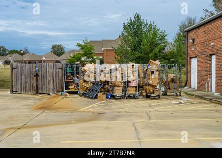 Trash and empty cardboard boxes piled up at a large dumpster with the cardboard boxes set for recycling. Stock Photo