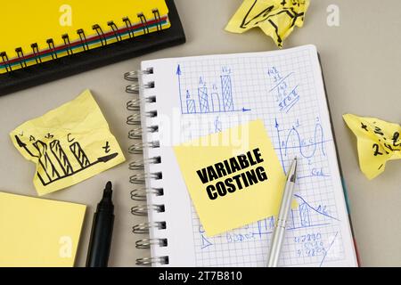 Business concept. On the table there is a notepad with notes and sticky notes with the inscription - Variable Costing Stock Photo