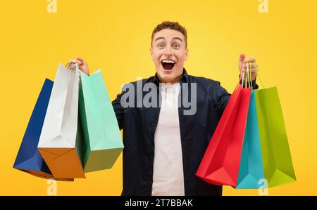 Happy young man going shopping, holding bags and looking excited Stock Photo