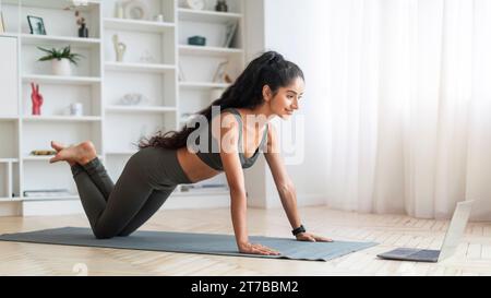 Sporty Millennial Indian Woman Undertaking Digital Exercise Session, Home Interior Stock Photo