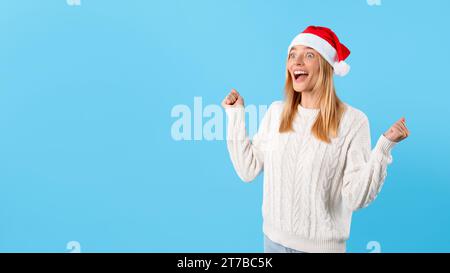 Excited woman in Santa hat celebrating clenching fists Stock Photo
