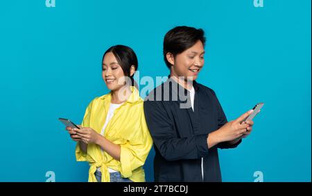 Cheerful chinese man in casual and woman chatting at smartphone at social networks Stock Photo
