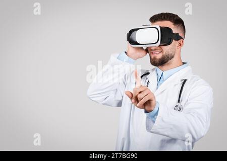 Doctor man using VR headset, pointing in air Stock Photo