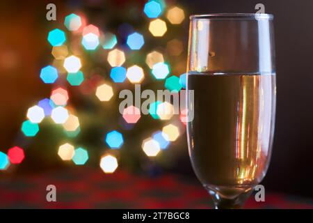Close up of champagne glass with selective focus, festive abstract background with beautiful bokeh of colorful lights and copy space for text. Christm Stock Photo
