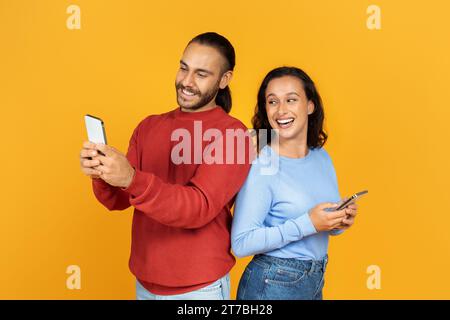 Portrait of smiling young woman looking at her boyfriend smartphone Stock Photo