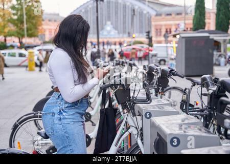 Young woman using rental bike in the city with smartphone Stock Photo