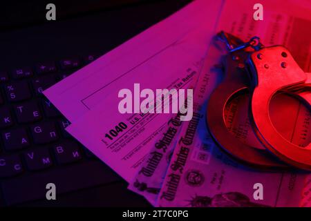 US Tax refund check and handcuffs on computer keyboard close up. Record criminal investigation Stock Photo