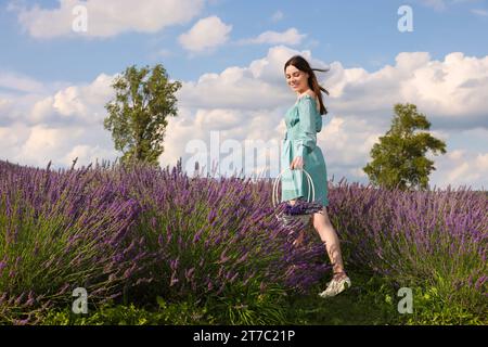 Beautiful woman with basket in lavender field. Space for text Stock Photo