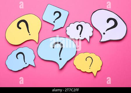 Different paper speech bubbles with question marks on pink background, flat lay Stock Photo