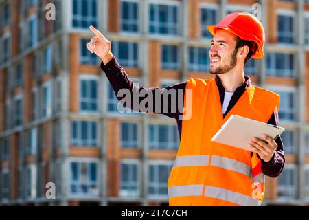 Medium shot portrait smiling architect pointing away Stock Photo
