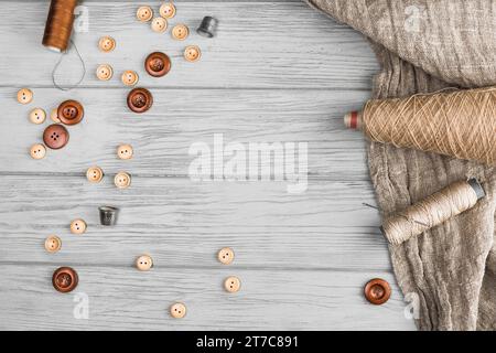 Top view button string spool needle thimble cloth wooden background Stock Photo