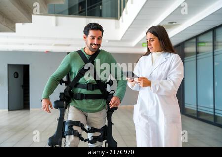 Mechanical exoskeleton, female doctor physiotherapist with disabled person with robotic skeleton in rehabilitation, physiotherapy in a modern Stock Photo