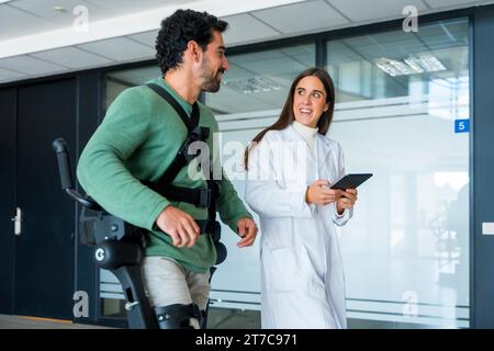 Mechanical exoskeleton, female doctor physiotherapist with disabled person with robotic skeleton in rehabilitation, physiotherapy in a modern Stock Photo