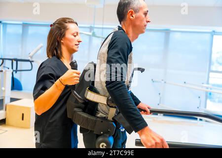 Mechanical exoskeleton. Female physiotherapy medical assistant helping disabled person with robotic skeleton to walk. Futuristic rehabilitation Stock Photo