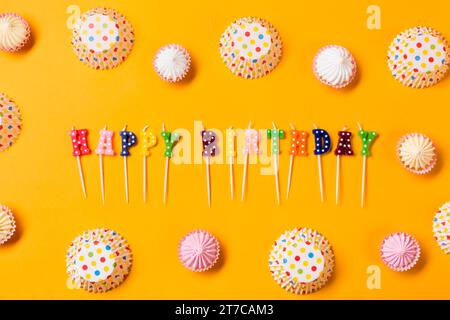 Colorful happy birthday candles decorated with aalaw polka dots paper cake forms yellow background Stock Photo