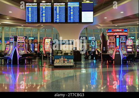 Las Vegas, Nevada, USA. Flight information monitors mingle with gaming machines at gate areas at Harry Reid International Airport. Stock Photo