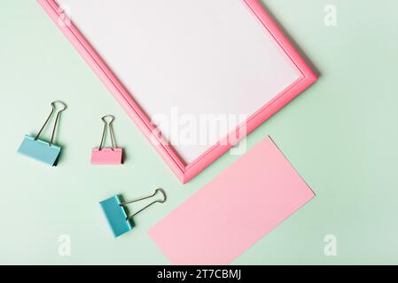 Overhead view paper clips blank pink paper white frame pastel colored background Stock Photo