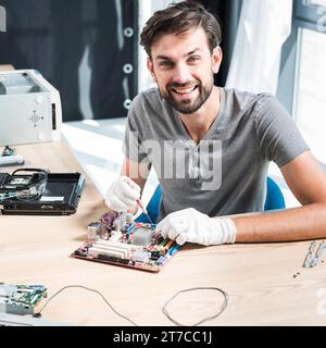 Portrait smiling male technician repairing computer motherboard Stock Photo