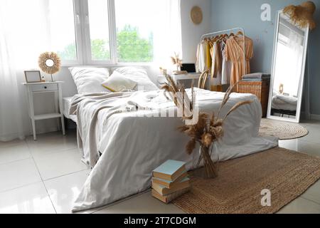 Interior of children's bedroom with cozy bed, laptop and clothes hanging on rack Stock Photo