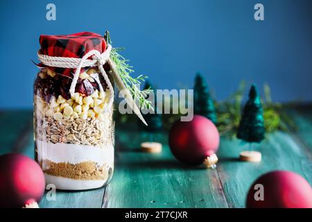 Gift of macadamia nut cookie dough recipe mixture of ingredients for baking cookies for Christmas.  Tied with a white string and greenery with paper t Stock Photo