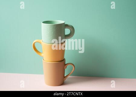 Stack of mug cup on pink table. mint green wall background Stock Photo