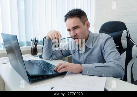 startup business, software developer working on computer at modern office. a thoughtful young handsome guy writes a program in a bright white office. Stock Photo