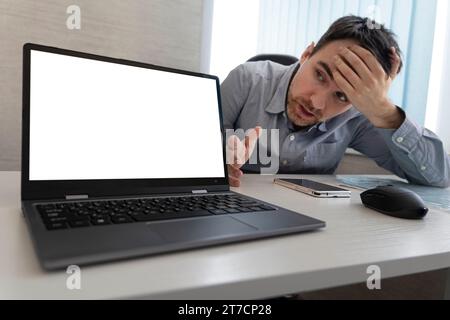 Thoughtful young 30s caucasian businessman in eyeglasses looking at computer screen, working distantly online at home office, solving problems, making Stock Photo