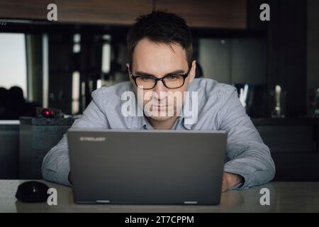 Thoughtful businessman think of online project looking at laptop at workplace, programmer writes a program at home with computer, student search new i Stock Photo