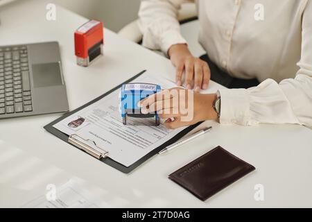 Close-up of woman putting stamp and approving documents for visa Stock Photo