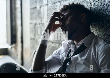 African American man with bandaged wrists having depression, he sitting alone in the room and worrying about his problems Stock Photo