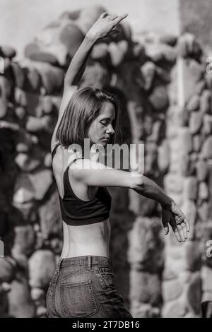 A black and white shot of a young woman wearing a black top and jeans. Stock Photo