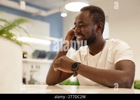African American young man having conversation on mobile phone while sitting in cafe Stock Photo