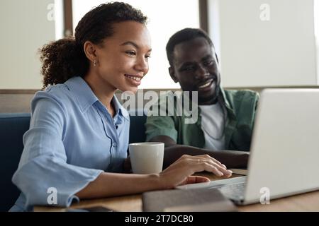 Young colleagues working online on laptop in coffee shop Stock Photo